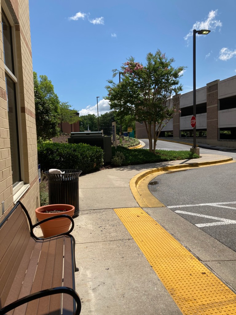 Photo showing sky, trees, bench in front of a building